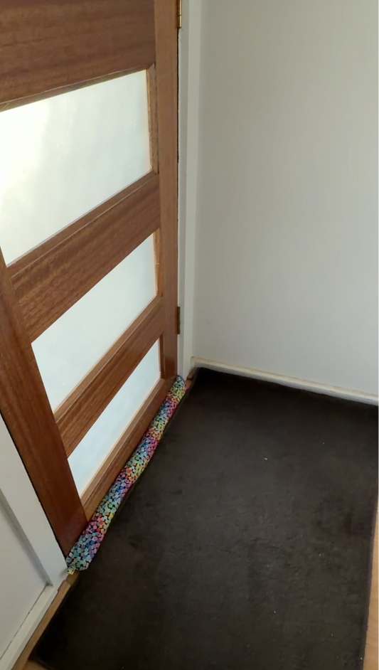 Wooden door with glass panels and a decorative draught stopper with a cat fabric cover at the base stopping a cold draught.