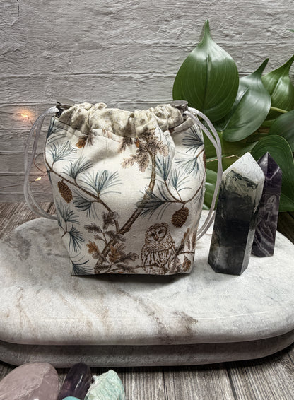 Drawstring bag with nature-themed design on a marble surface with crystals and plants.