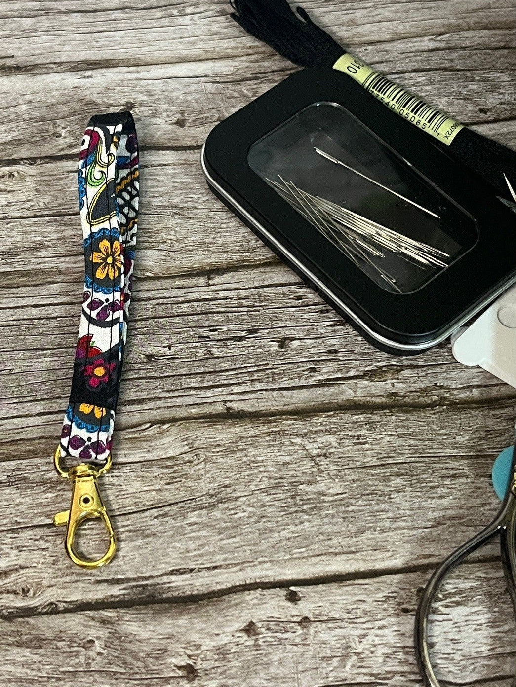 Colorful scissor fob with key chain keychain with a black case and scissors on a wooden surface