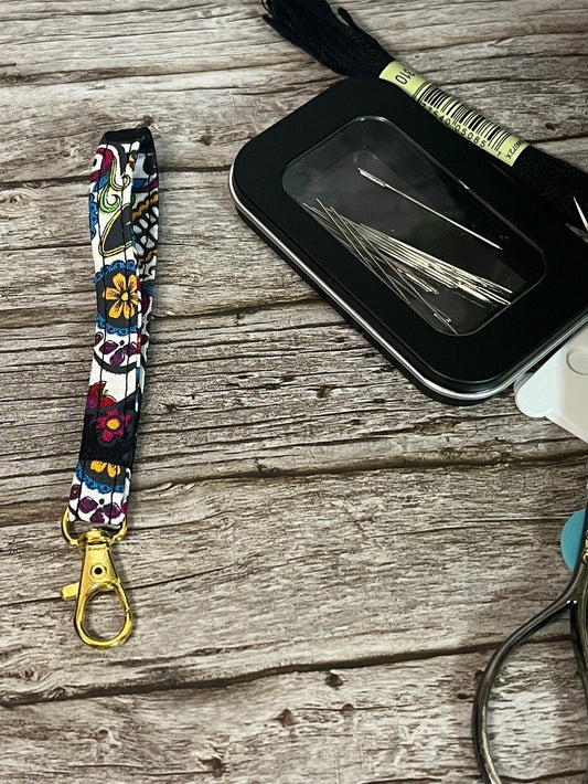 Colorful scissor fob with key chain keychain with a black case and scissors on a wooden surface