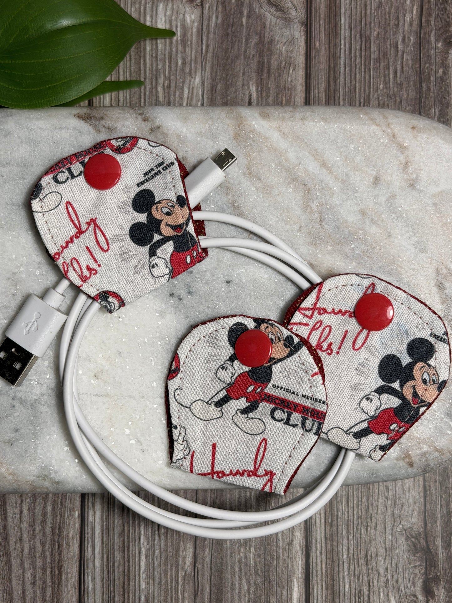 Mickey Mouse cable organiser with a mobile phone charger on a marble surface 