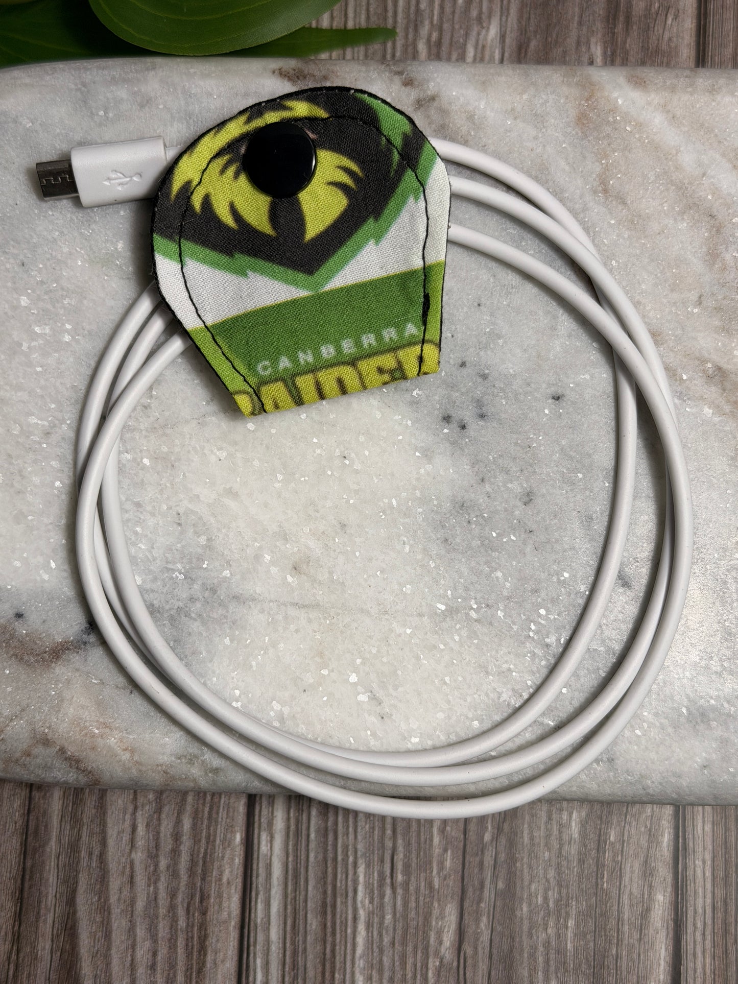 Viking cable organiser with a mobile phone charger on a marble surface 