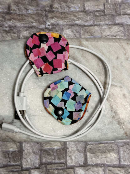 Two colorful cable organisers styled on a coiled cable on a stone surface