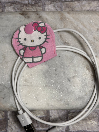 Hello Kitty cable organiser with a mobile phone charger on a marble surface 