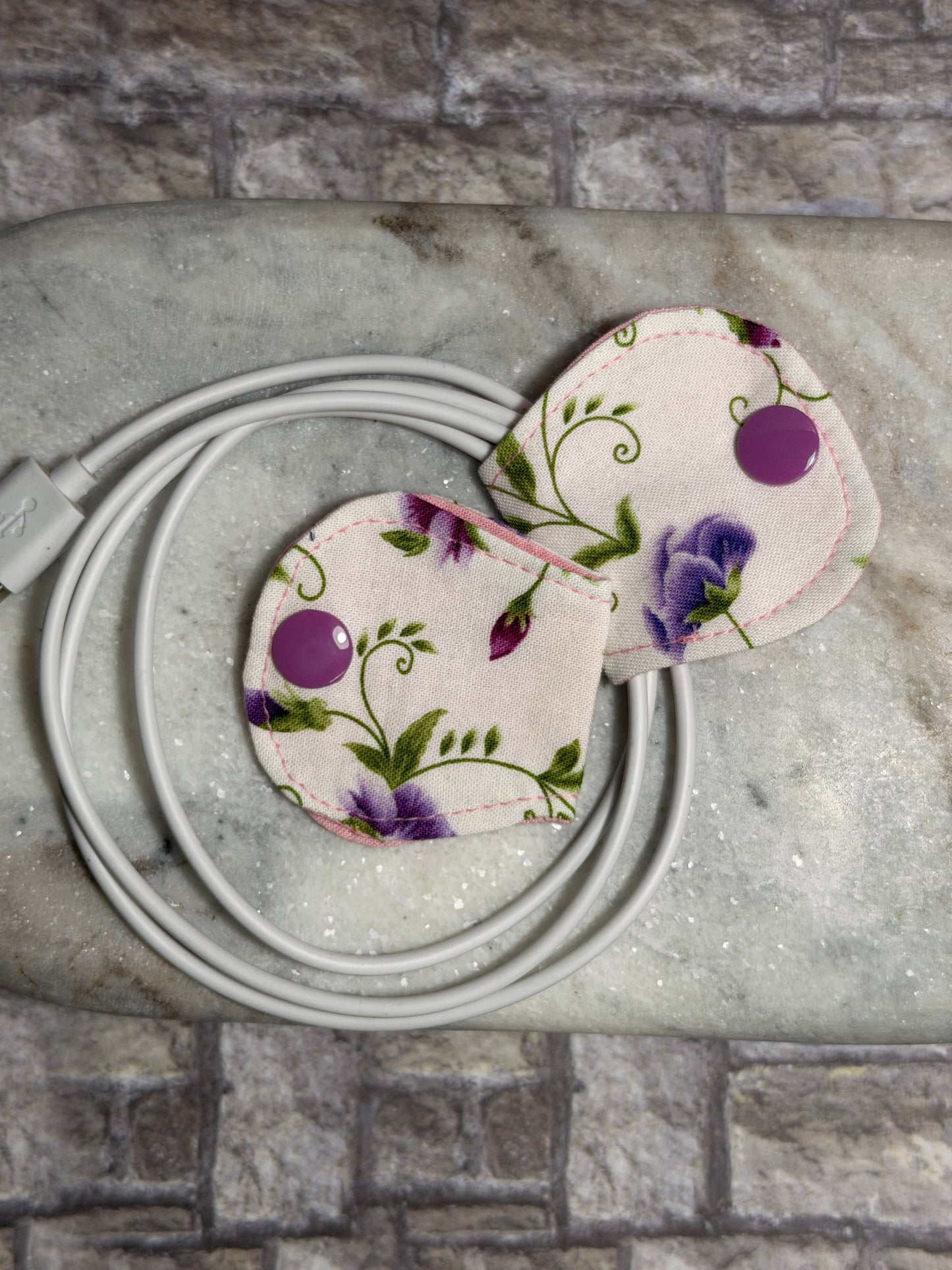 Floral cable organiser with a mobile phone charger on a marble surface 