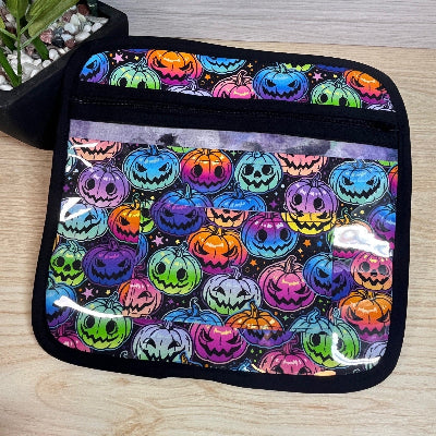 Colorful Halloween-themed cross stitch project bag with pumpkins on a wooden surface