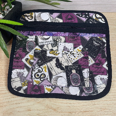 Small cross stitch project bag with a black border featuring a pattern of tarot cards and designs on a wooden surface.