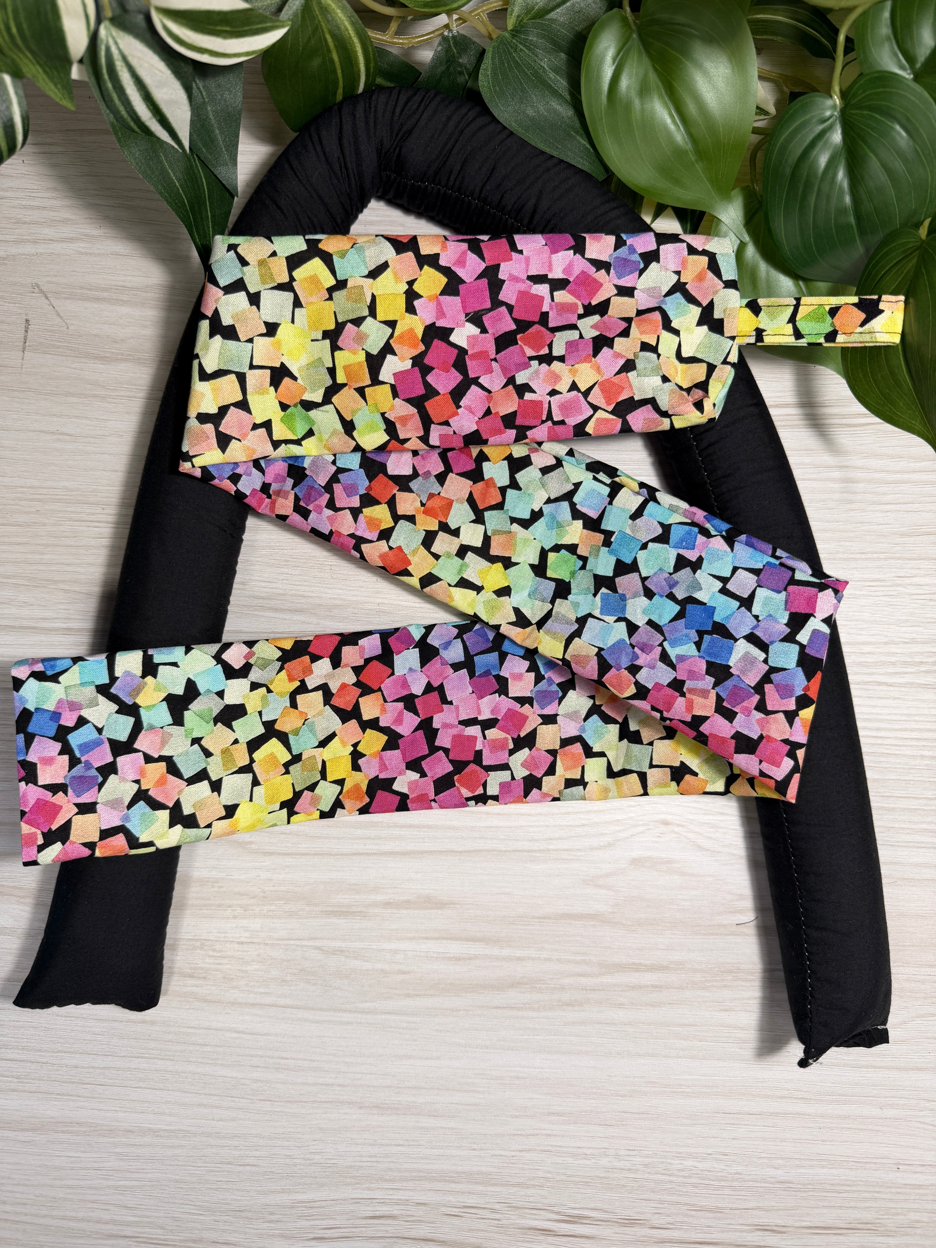 Colourful-patterned draught stopper cover sitting on a the draught stopper insert  against a wooden background