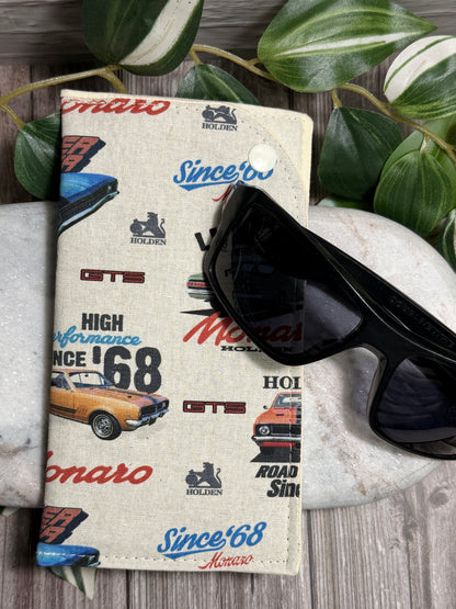 Glasses Case with vintage car brand designs and sunglasses on a stone surface with leaves in the background