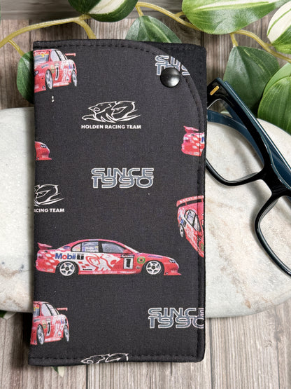 Glasses Case with a Black Holden Racing Team car illustrations on a wooden surface. with glasses