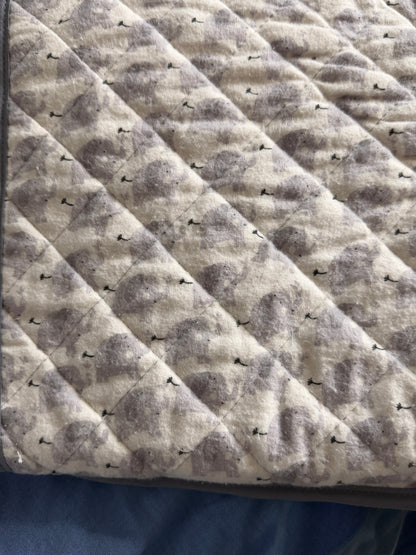 Close-up of a quilted fabric snuggle blanket with a gray and beige elephant pattern, stitched in a diamond pattern.