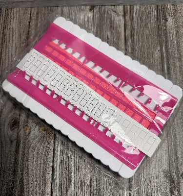Pink cross stitch / hand stitching floss needle parking organiser on a wooden surface