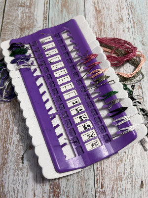 Purple cross stitch / hand stitching floss needle parking organiser on a wooden surface