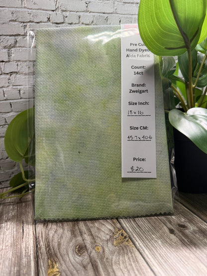 Green cross stitch adia fabric with a label on a wooden surface