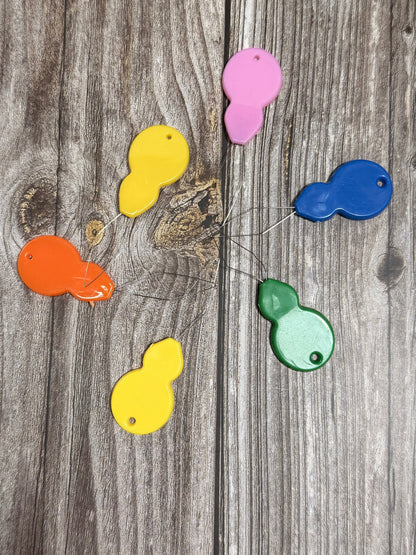 Colorful long looped needle threaders on a wooden surface