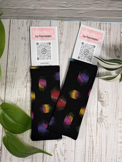 Fabric Icy Pole Holder with Black background with colorful pattern on a wooden surface with plant leaves.