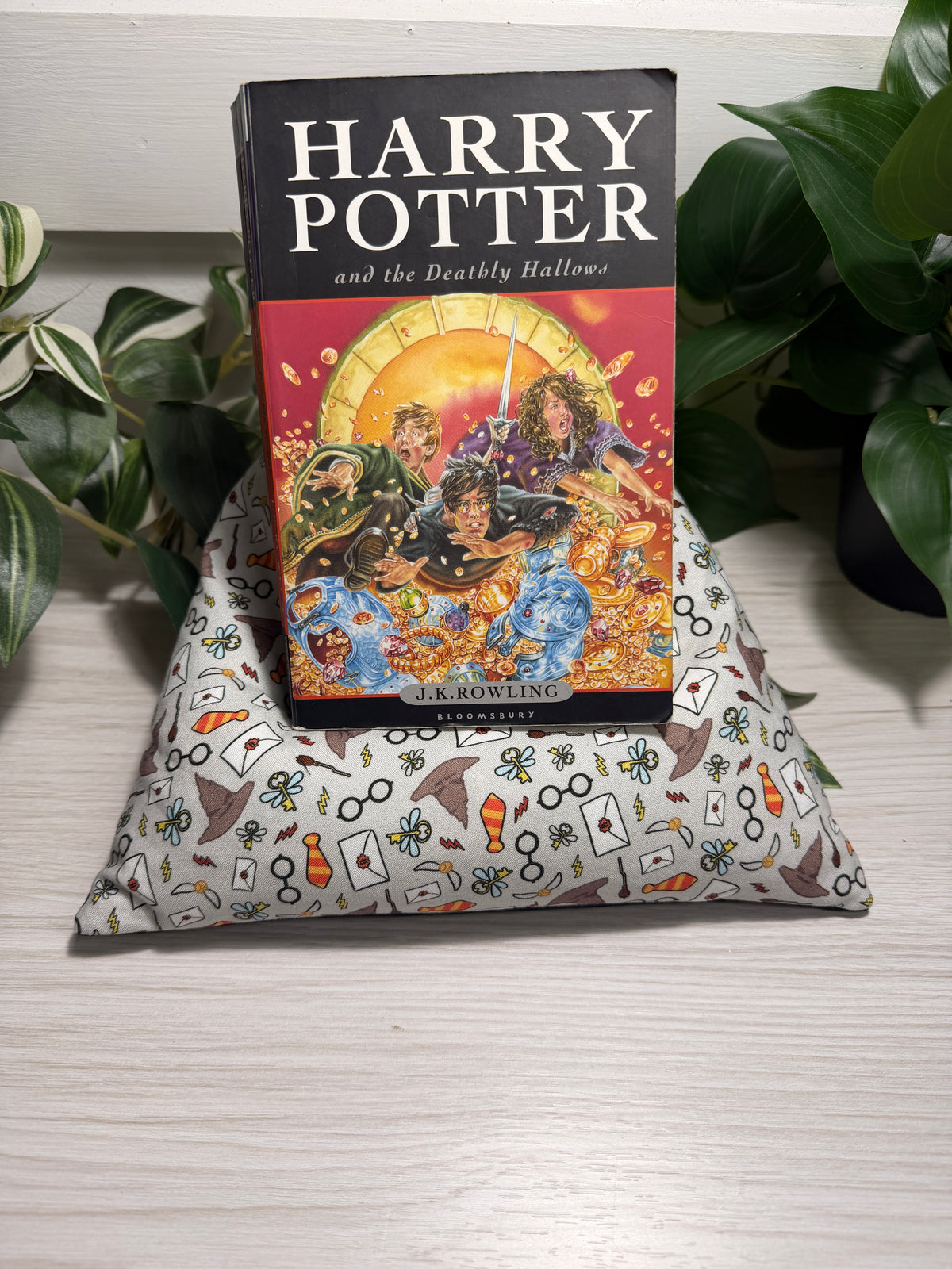 A copy of the Harry Potter and the Deathly Hallows book placed on a lap pillow with a harry potter fabric