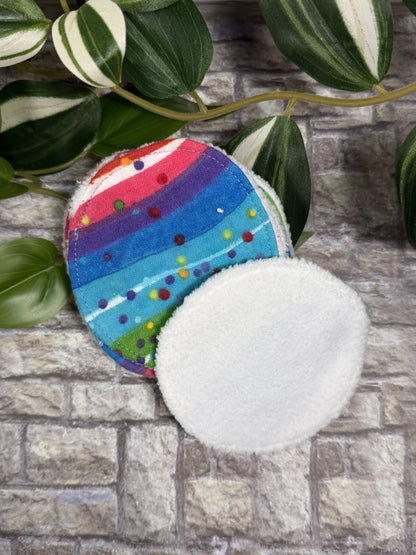 Round fabric face cleanser and make up remover pads with Colorful striped fabric circle with a stone wall background