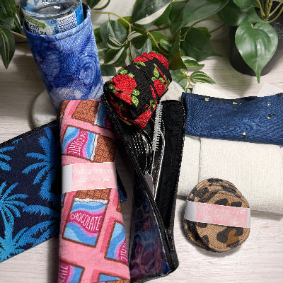 Collection of items including a water bottle, utensils, and a small round container on a marble surface with plants.