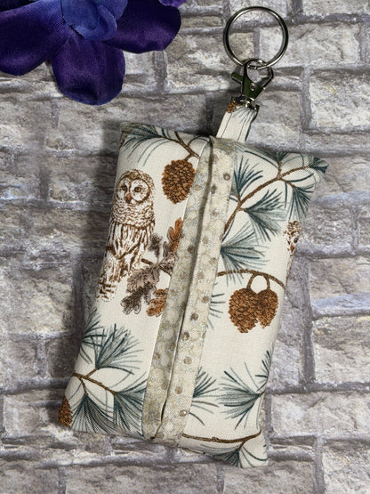 Fabric tissue pouch with woodland and owls pattern on a keychain against a stone wall background
