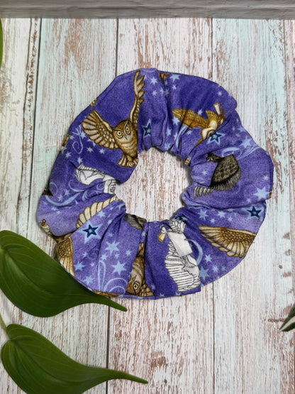 Purple scrunchie with owls design on a wooden surface