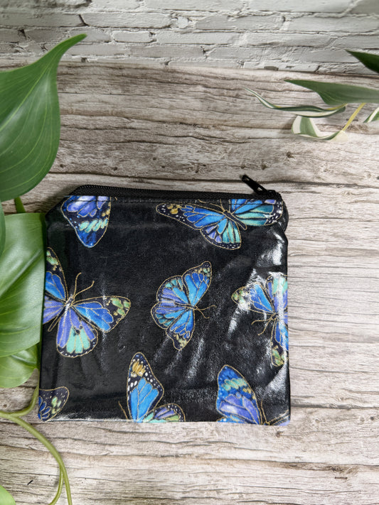 Black pouch with blue butterfly design on a wooden surface