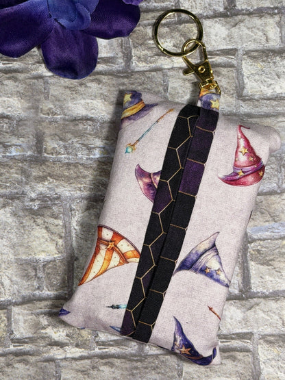 Fabric tissue pouch with a magical hats pattern on a keychain against a stone wall background