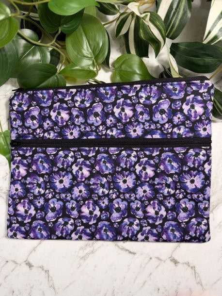 Purple floral patterned device sleeve on a marble surface with green leaves in the background