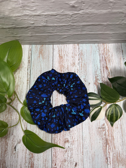 Blue scrunchie on a wooden surface with green leaves